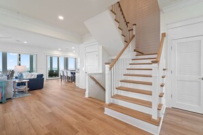 Un vaste espace de vie agrémenté d’un escalier en bois, de grandes fenêtres et d’une vue sur l’extérieur.