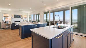 Een moderne keuken met een groot eiland, een eetgedeelte met uitzicht, en een ruime woonkamer.