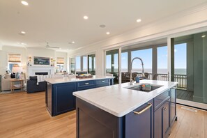 Een moderne keuken met een groot eiland, een eetgedeelte met uitzicht, en een ruime woonkamer.