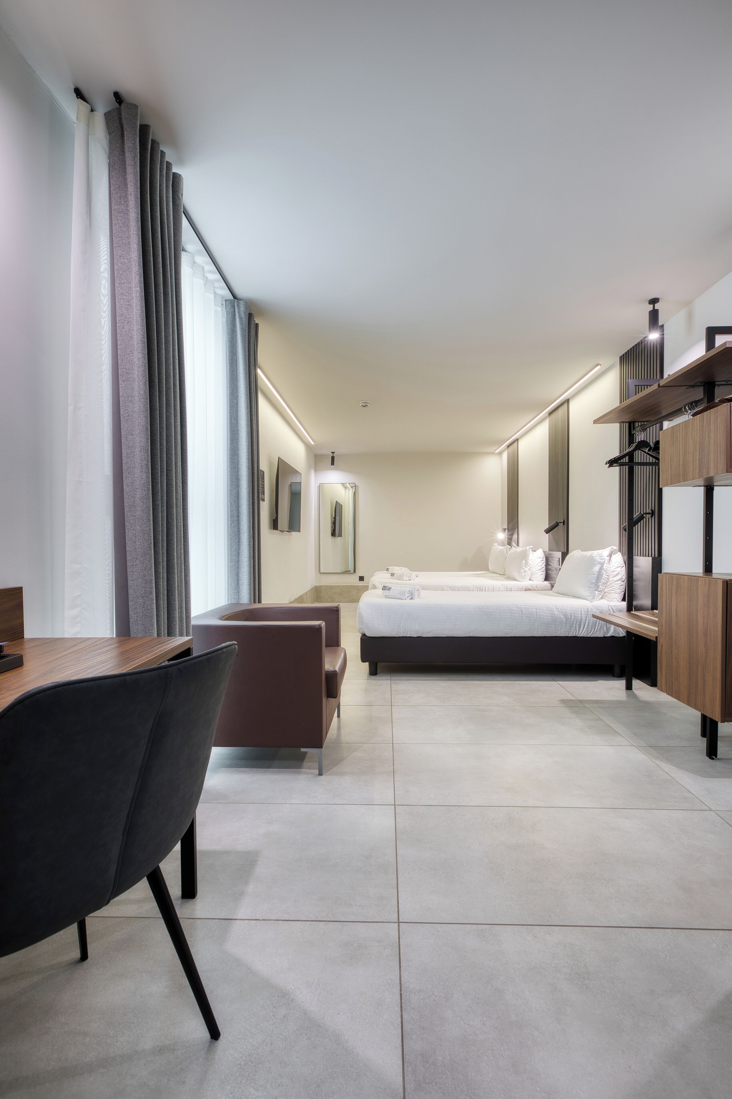 Een moderne hotelkamer met een bed, een bureau, een stoel en een kledingkast.