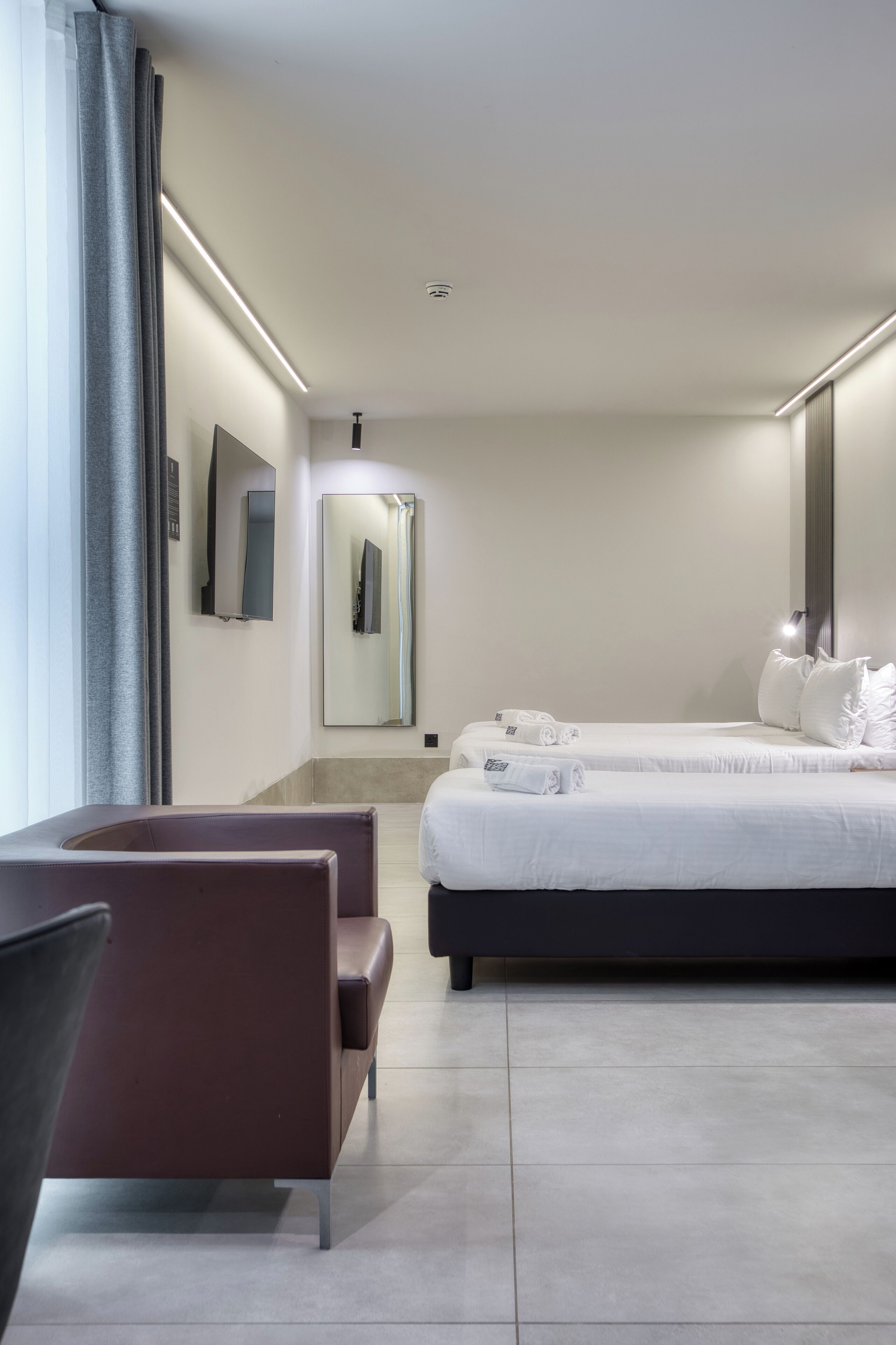A modern hotel room with a large bed, a seating area, and a mirror.