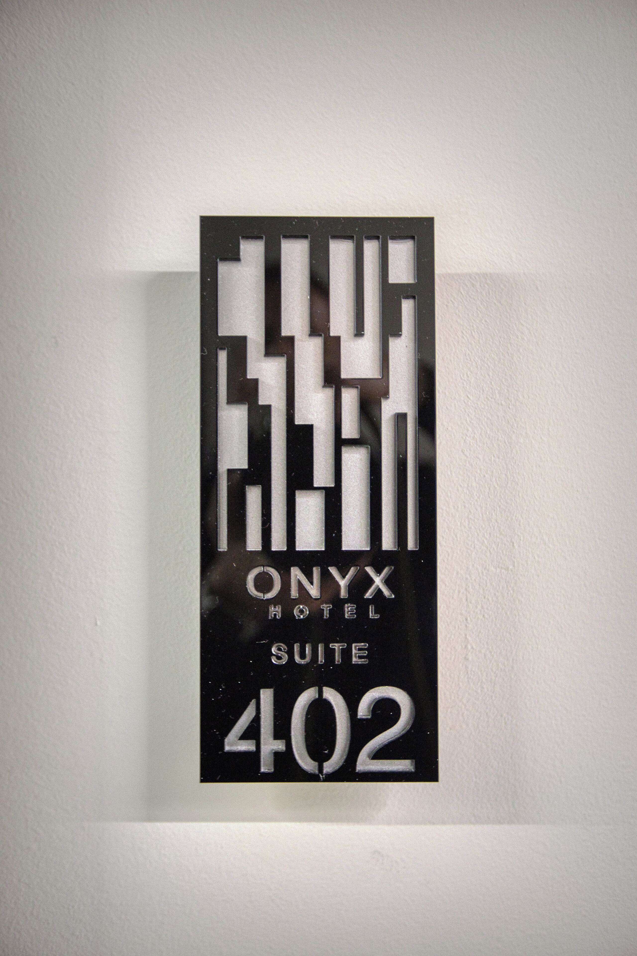 A hotel sign with the name "ONYX HOTEL SUITE 402" in a modern, geometric design.