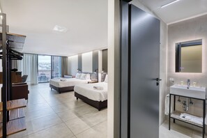 A hotel room with two beds, a balcony with a city view, a modern bathroom with a sink and mirror, and a wooden shelf with books. - Onyx Hotel (St. Julian's)