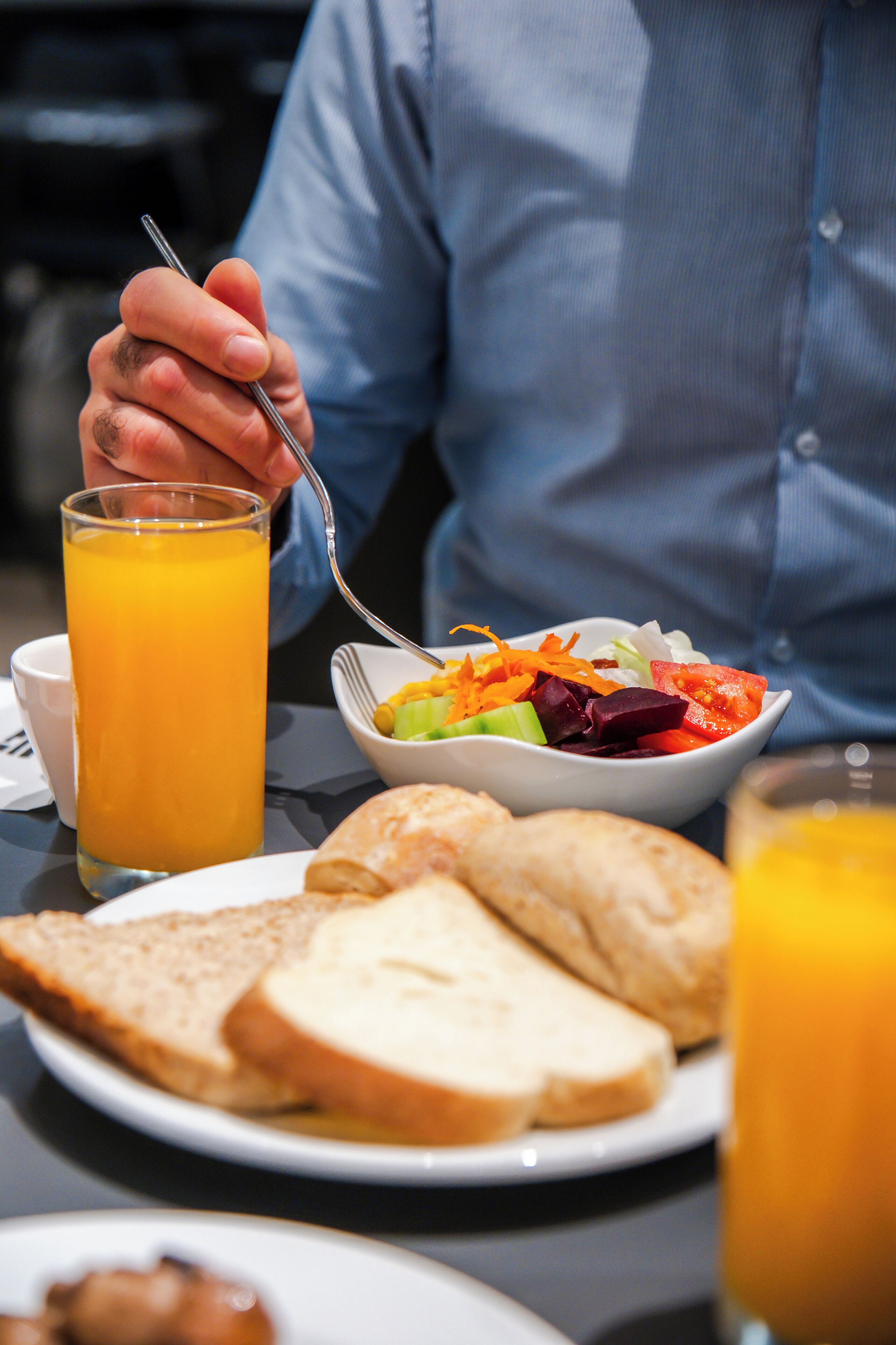 A breakfast setting with a glass of orange juice, a bowl of salad, and slices of toast on a table.