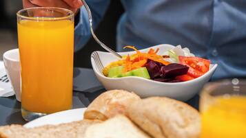 A breakfast setting with a glass of orange juice, a bowl of salad, and slices of toast on a table.