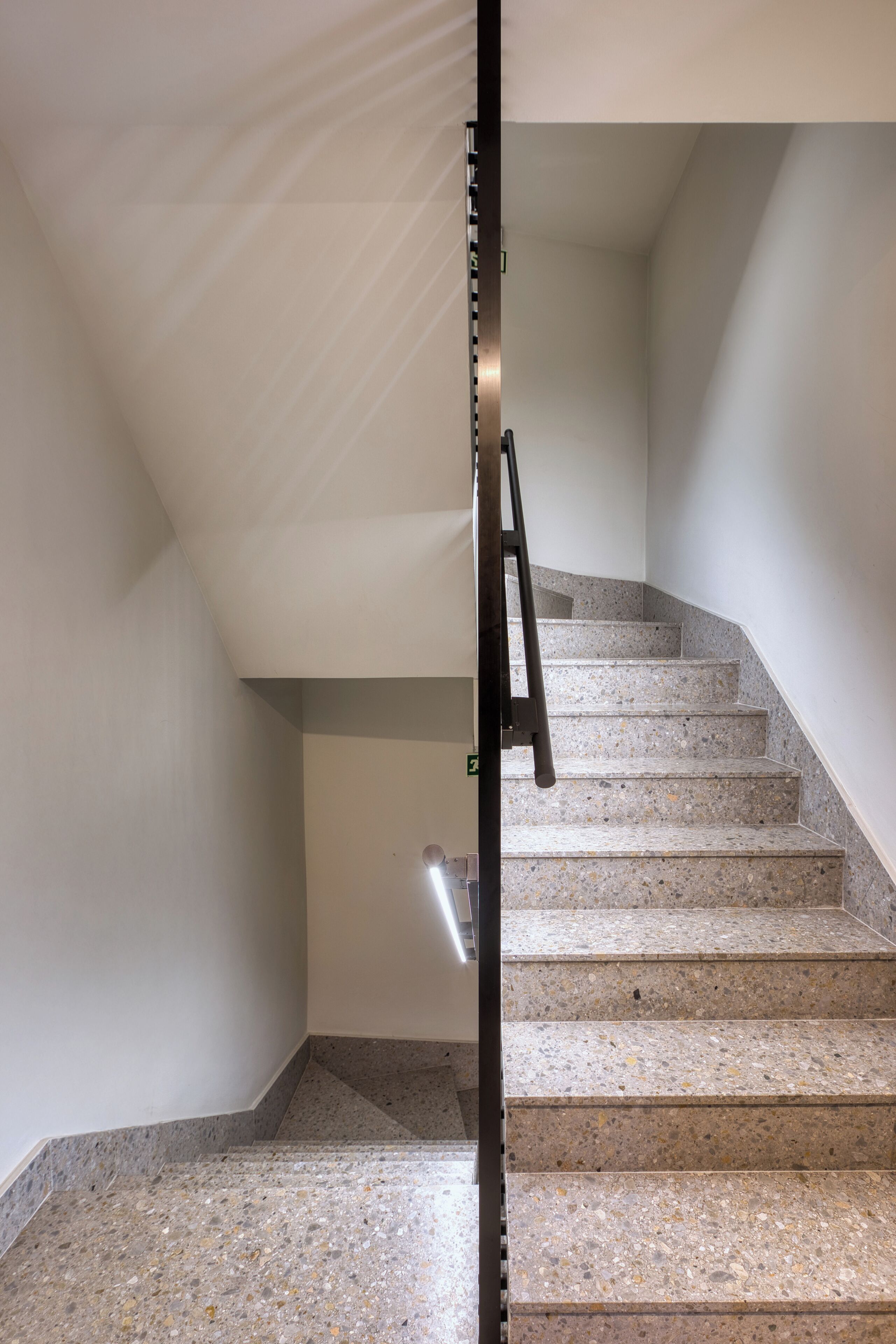 A staircase with a handrail and a door at the bottom.