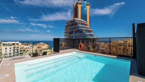 Ein Pool auf dem Dach mit Blick auf ein hohes Gebäude und das Meer.