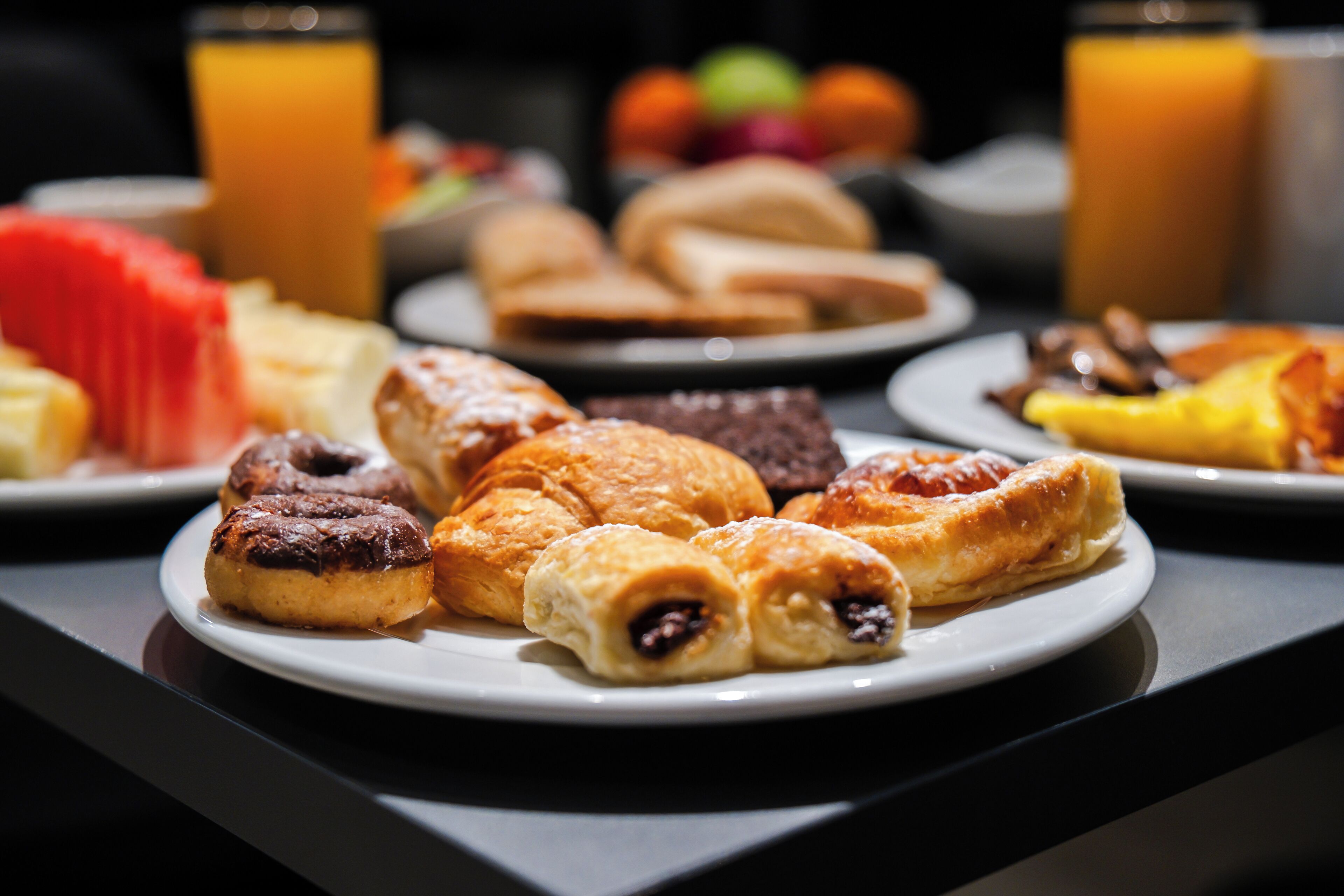 A breakfast buffet with various pastries, fruits, and juices.