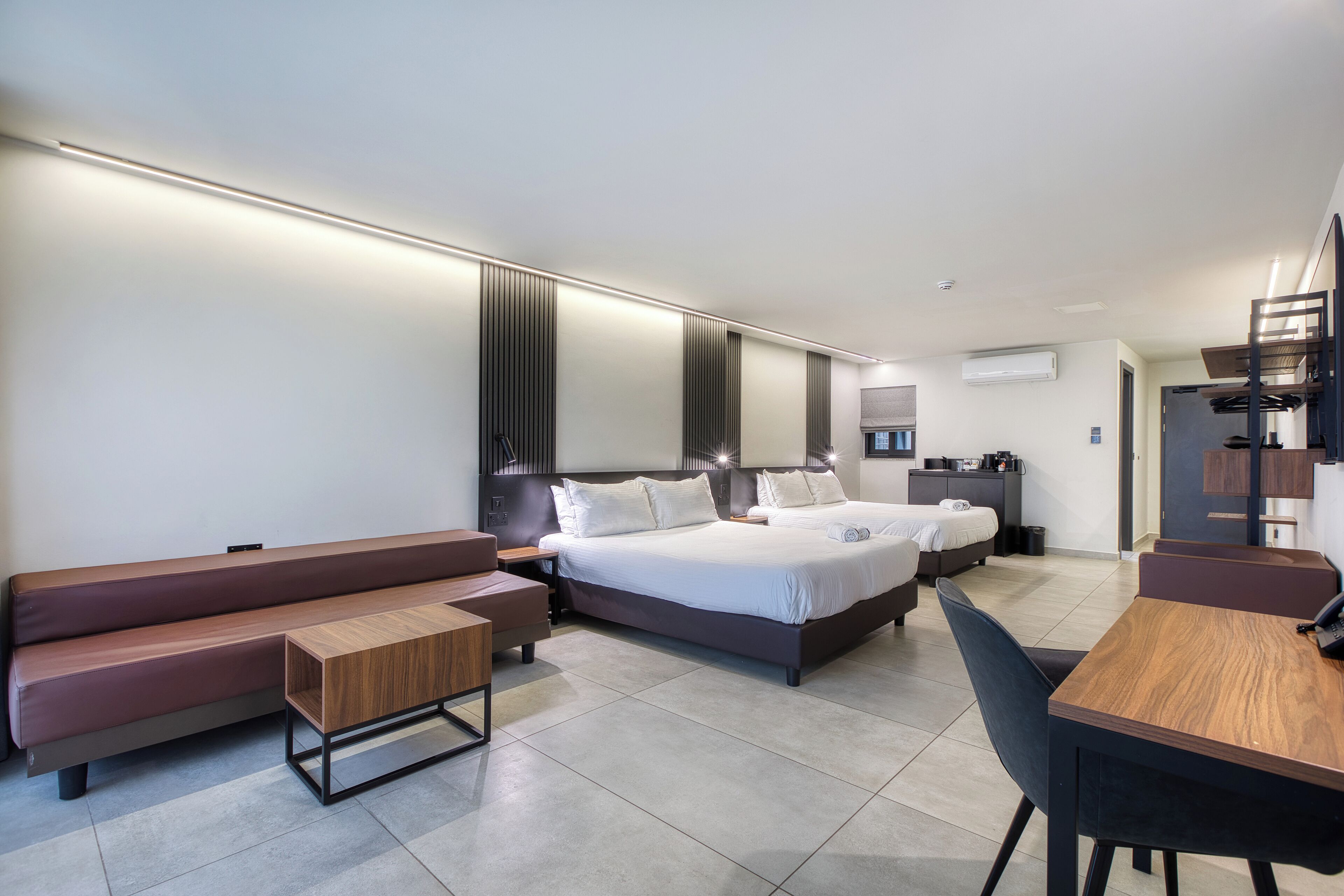 A modern hotel room with a large bed, a sofa, a desk, and a chair.
