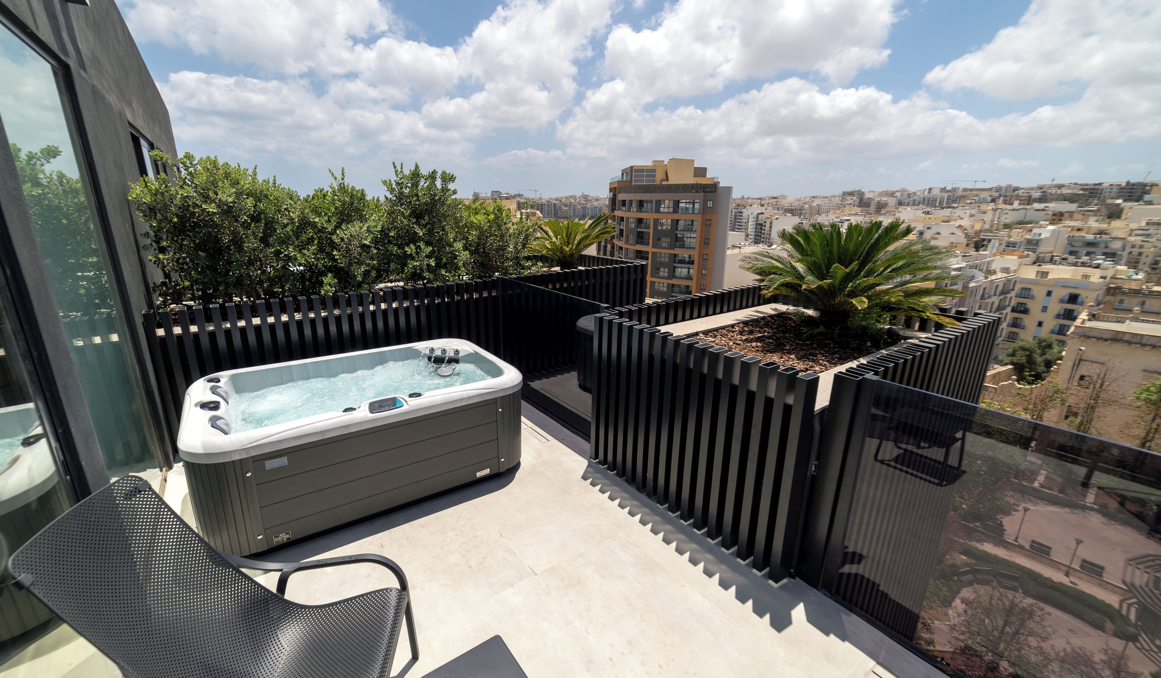 Una terraza en la azotea con jacuzzi, asientos y vistas a la ciudad.