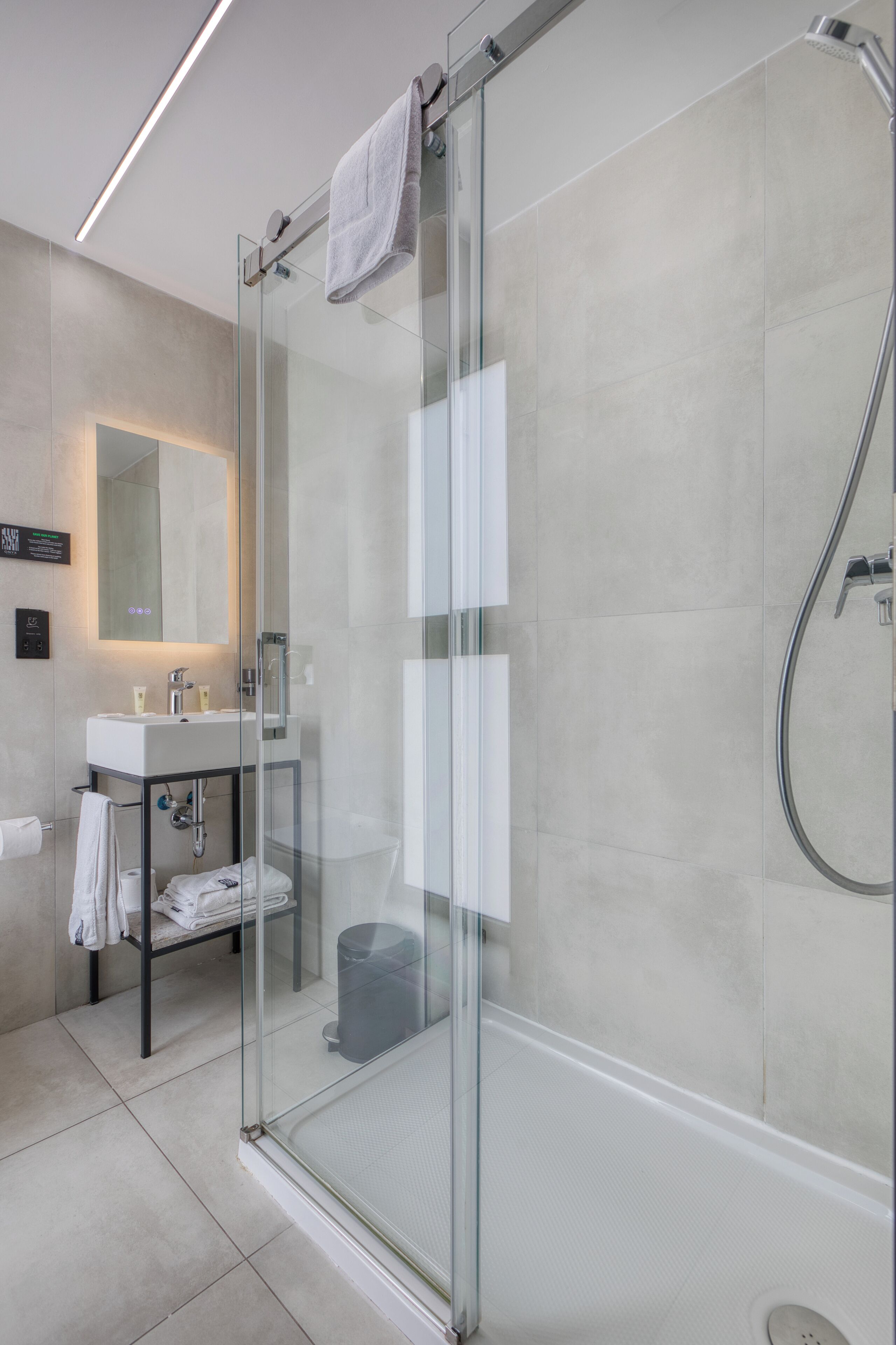 A modern bathroom with a glass-enclosed shower, a sink, and a mirror.