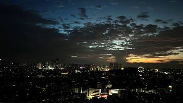 A nighttime cityscape with illuminated buildings and a cloudy sky.