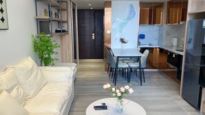 Un salon moderne avec un canapé blanc, une table basse ornée d’un vase de fleurs et un coin repas avec une table et des chaises blanches.