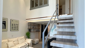 Un salon moderne avec un escalier, un canapé, une table basse et une plante.