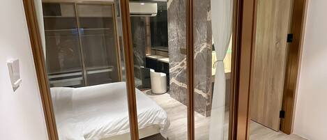 A bedroom with a bed, a wardrobe, and a bathroom.