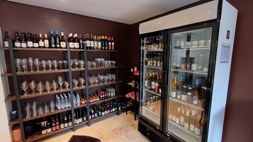 Une pièce équipée d’un présentoir pour les vins et les spiritueux, d’étagères remplies de bouteilles de vin et d’un grand réfrigérateur.