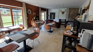 A modern kitchen with a dining area, large windows, and a fireplace. - B&B Madoli (Erezee)