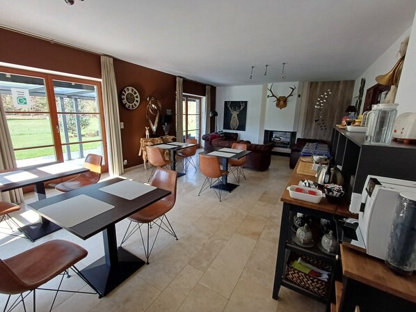 A modern kitchen with a dining area, large windows, and a fireplace. - B&B Madoli (Erezee)