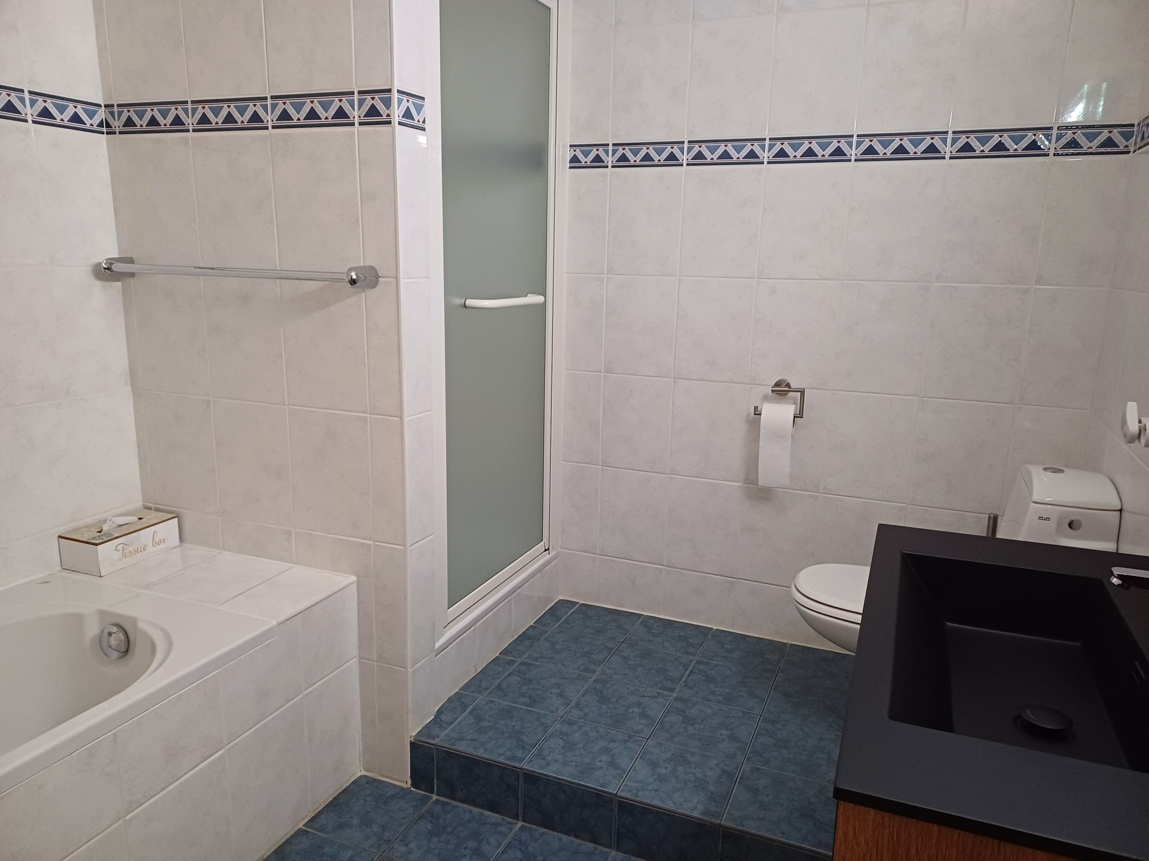 Ein modernes Badezimmer mit Badewanne, Toilette und Duschbereich.