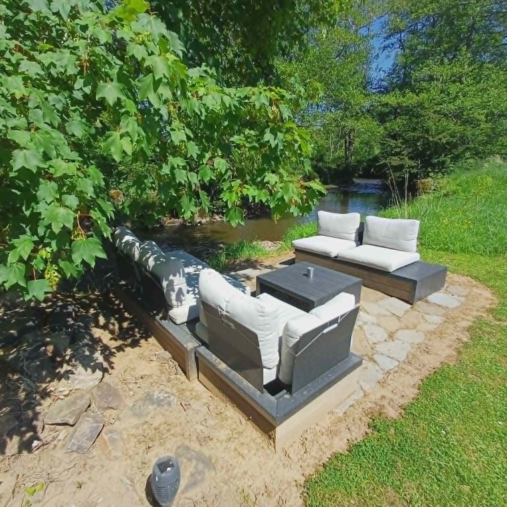 An outdoor seating area with a stone fire pit and cushions.