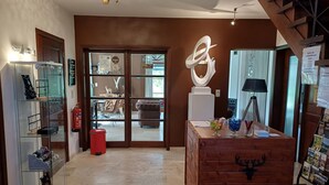 A hotel lobby with a glass display case, a wooden dresser, and a large abstract sculpture. - B&B Madoli (Erezee)
