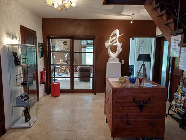Un hall d’hôtel avec une vitrine, une commode en bois et une grande sculpture abstraite.