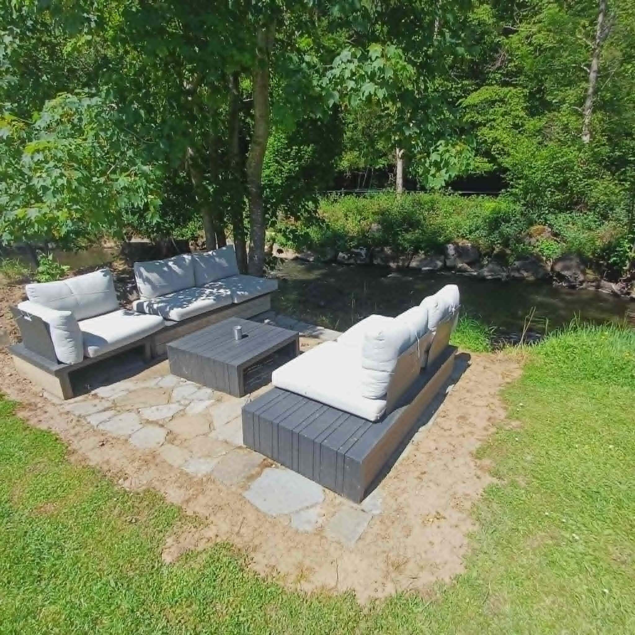 Un área de estar al aire libre con suelo de piedra, dos sofás y una mesa.