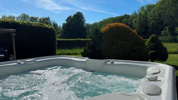 Een bubbelbad met uitzicht op de tuin en bomen eromheen.