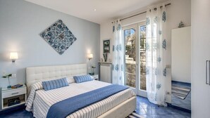 A bedroom with a bed, nightstands, a radiator, and a view through a glass door.