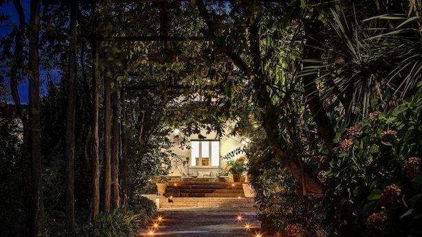 A pathway leading to a building with a window and steps, surrounded by dense foliage and decorative lights. - Casa Bianca in Massa Lubrense (Massa Lubrense)
