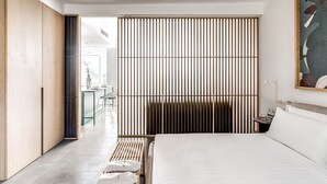 A modern hotel room with a large bed, a wooden wardrobe, a sliding shoji screen, and a dining area visible through an open door. - Suite La Panoramica in Sant Agata sui Due Golfi (Massa Lubrense)