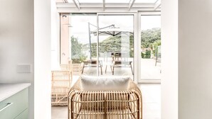 A bright room with a glass door leading to an outdoor area. There is a wicker chair and a table with chairs outside. - Suite La Panoramica in Sant Agata sui Due Golfi (Massa Lubrense)