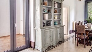 Un coin repas comprenant une table en bois, des chaises et un meuble contenant des objets décoratifs.