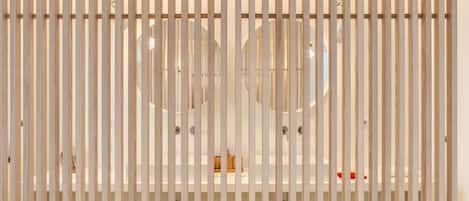 A modern bathroom with a white bathtub, vertical wooden slats, and circular mirrors.