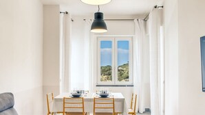 A dining area with a table set for four, a sofa, and a TV stand. - Casa Tit in Massa Lubrense (Massa Lubrense)
