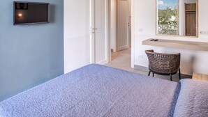 A bedroom with a bed, a chair, a desk, a mirror, and a television on the wall. - Casa Tit in Massa Lubrense (Massa Lubrense)