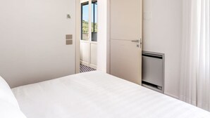 A hotel room with a bed, a door leading to a balcony, and a small TV. - Le Arcate Giuliana in Massa Lubrense (Massa Lubrense)