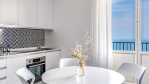 A modern kitchen with white cabinets, a patterned backsplash, and a round dining table with chairs. - Le Arcate Giuliana in Massa Lubrense (Massa Lubrense)