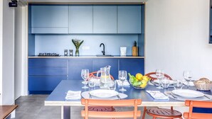 A modern kitchen with blue cabinets, a dining table set with chairs, and a kitchen island with a sink and countertop. - M3 - Magma in Sant Agata sui Due Golfi (Massa Lubrense)