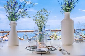 A table set for dining with vases of flowers, clear glasses, and cutlery. - Villa Mediterranea in Citt Metropolitana di Napoli (Massa Lubrense)