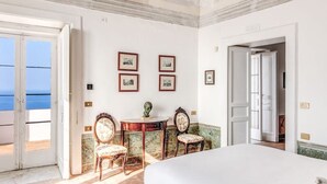 Une chambre d’hôtel avec un grand lit, un bureau, deux chaises, un lustre et des tableaux encadrés au mur.