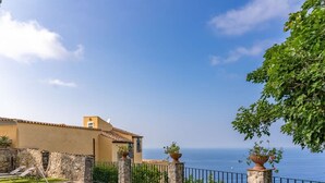 Une piscine bordée de pierres, un mur en pierre et une vue sur la mer.