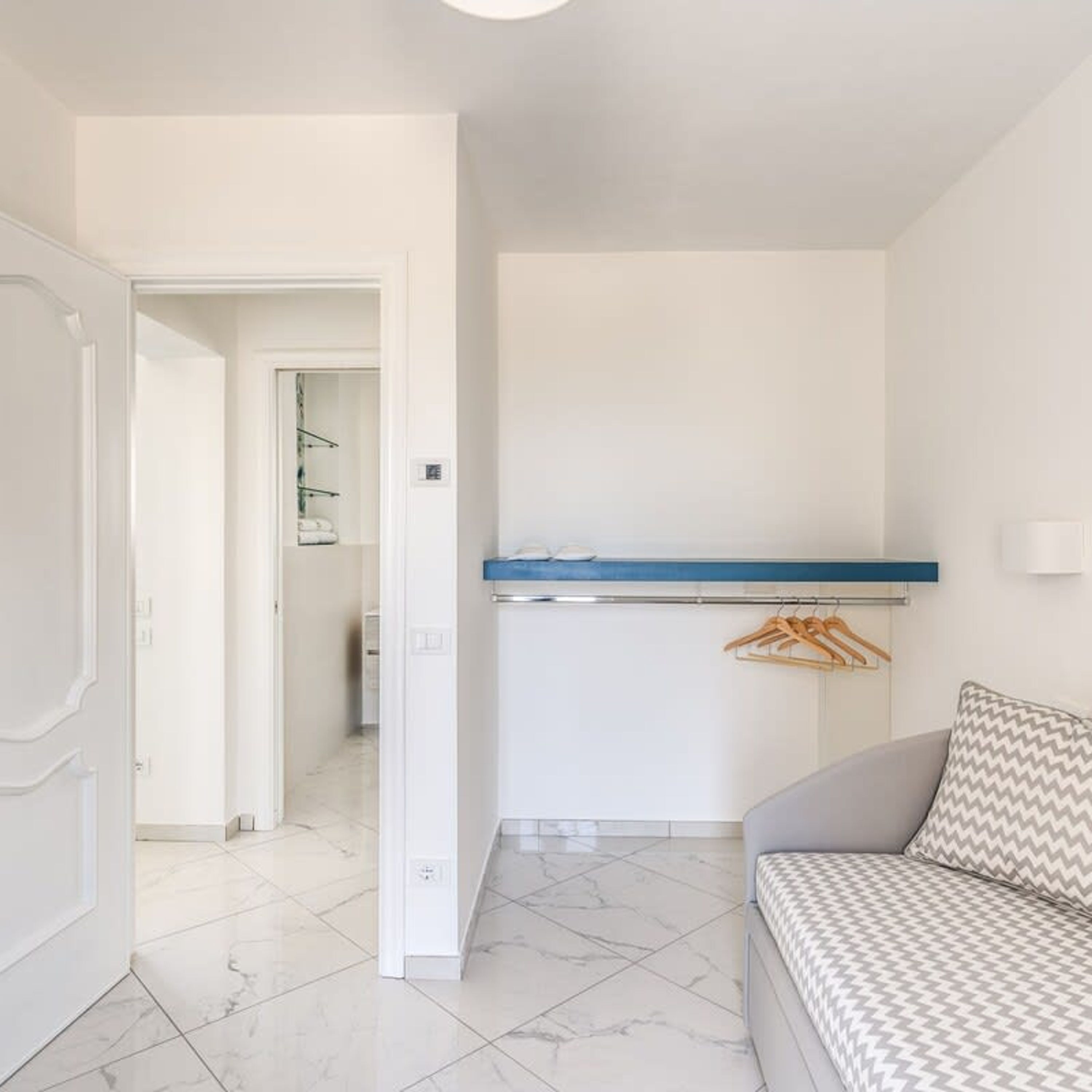 A compact living space with a kitchenette, a sofa, and a door leading to another room.