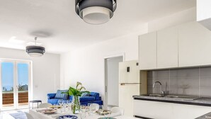 A modern kitchen with white cabinets, a marble countertop, and a dining area with a white table set for four. - Villa Rusinella in Massa Lubrense (Massa Lubrense)