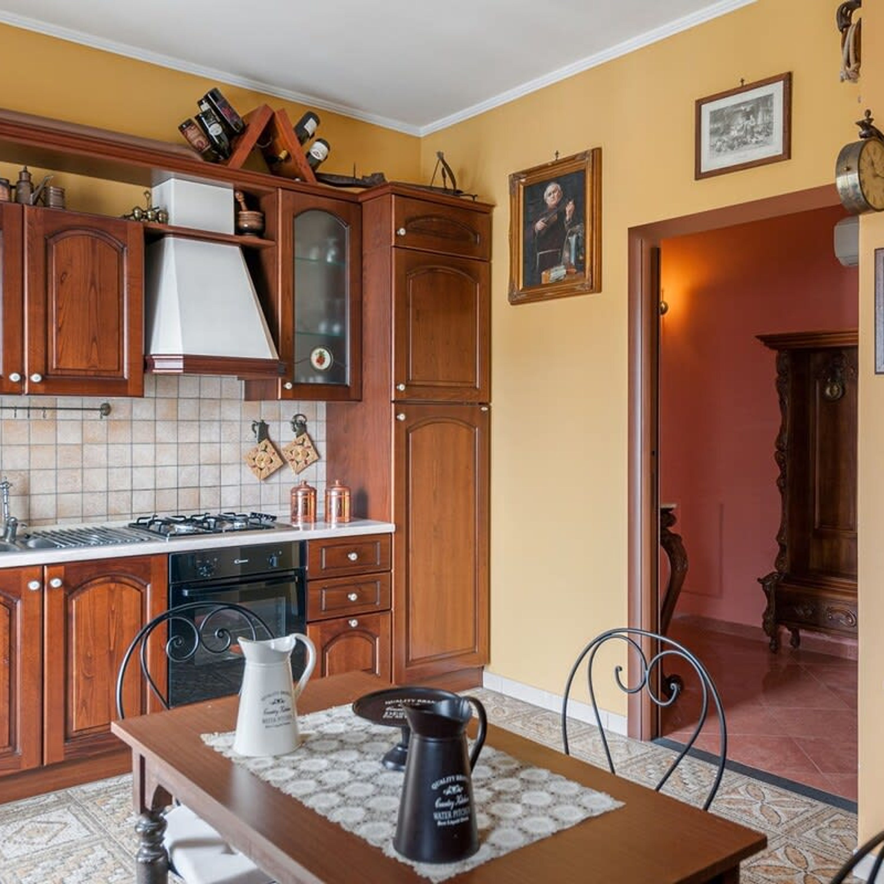 Cozinha com armários de madeira, fogão e mesa de jantar com cadeiras.