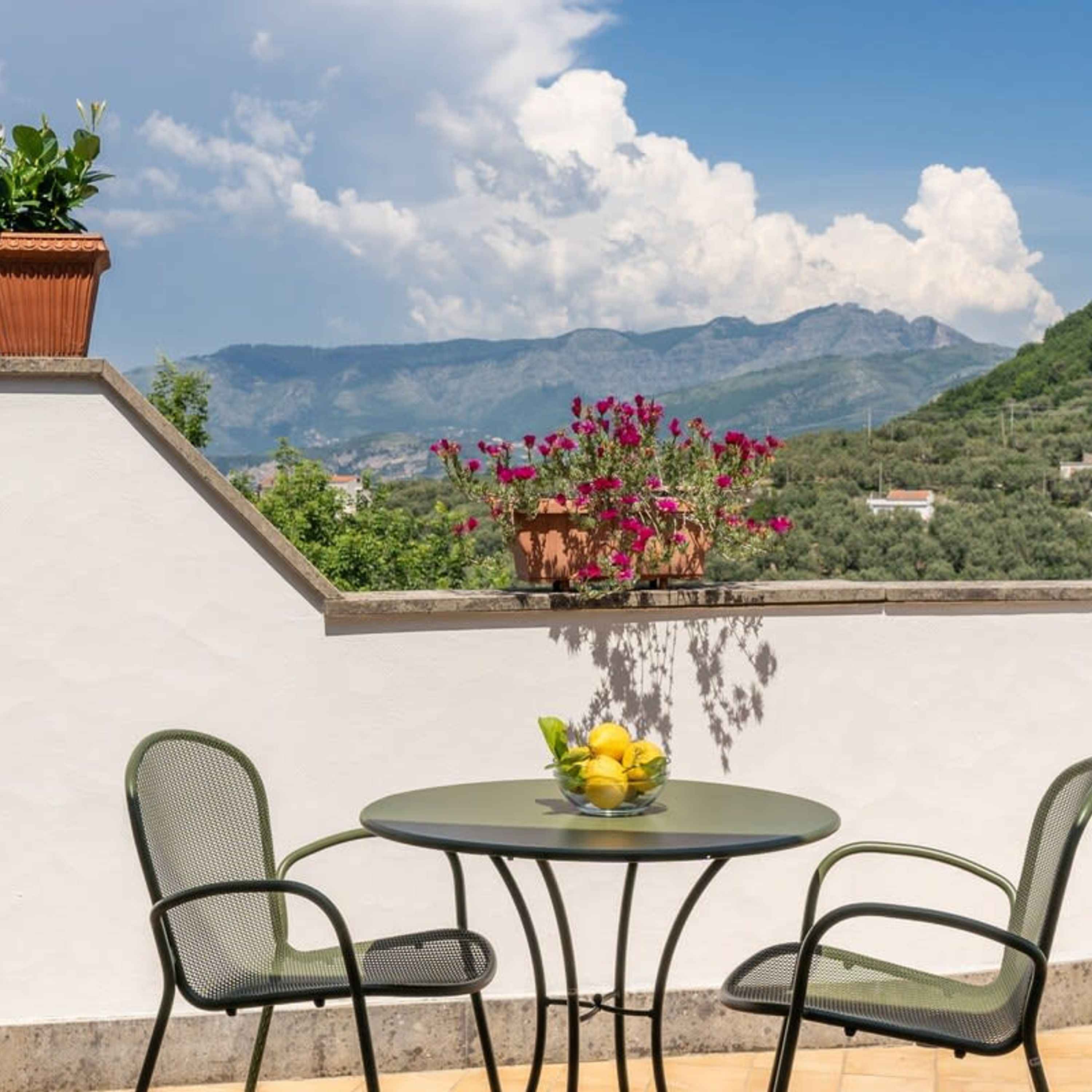 Una terraza con una mesa y sillas, una planta en maceta y vistas a montañas.