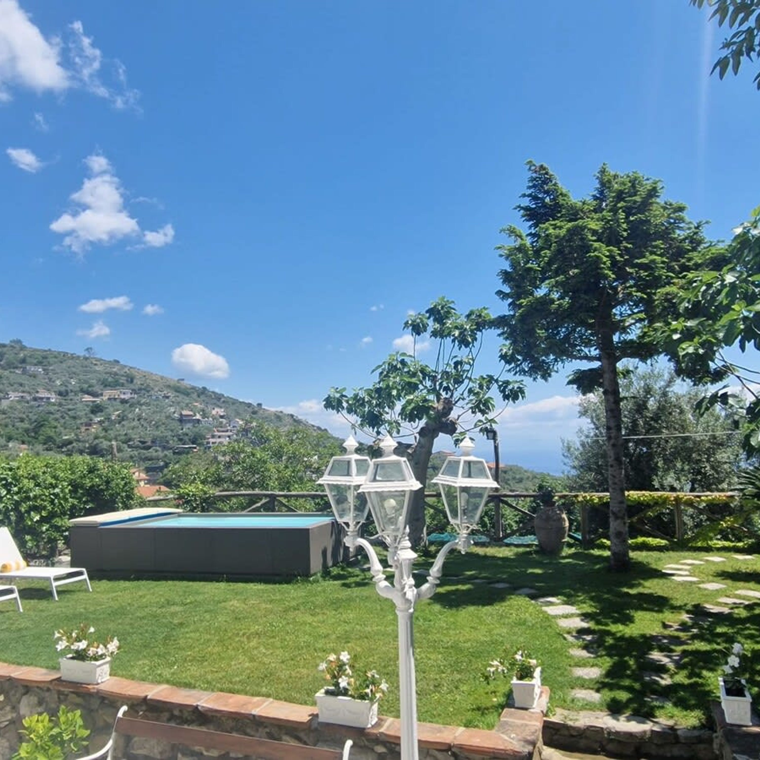 Un patio trasero con piscina, un farol y vistas a un paisaje montañoso.