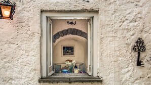 Fachada rústica de edificio con una pequeña ventana con un arco decorativo, un aplique de pared y una cerradura.