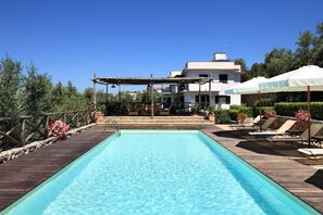A rectangular swimming pool with a wooden deck, lounge chairs, and umbrellas. - Le Capannelle - Turandot (Massa Lubrense)