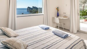 Une chambre avec un lit, un bureau et une vue sur la mer.